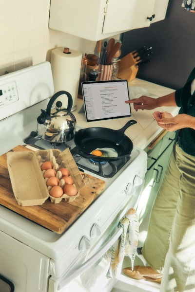 Fornuis met een theepot en pan waarin een ei gebakken wordt